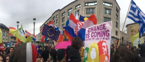 Foto einer Demo mit eurpäischen Fahnen und einem Transparent mit der Aufschrift: Change is coming, wether they like it or not